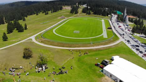 Sports-Resort-hotel-in-Slovenia-with-ski-lift,-bike-pump-track-and-soccer-field-with-people-on-sunny-day,-Aerial-flyover-shot