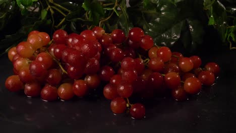 Seedless-red-grapes-on-a-black,-wet-surface
