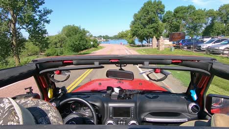 POV-Driving-towards-and-along-a-lake-in-rural-South-Dakota-with-the-top-off-of-a-red-vehicle