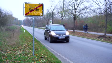 Leaving-Berlin-Town-Sign-next-to-Road-with-driving-Car-in-Autumn