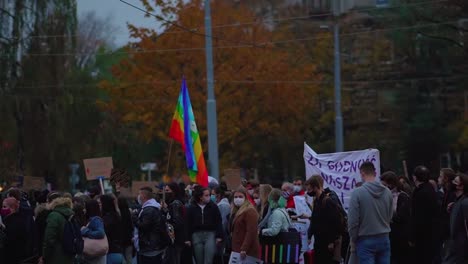 Protesters-Marching-On-The-Street-Of-Szczecin,-Poland-Carrying-Pace-Rainbow-Flag---wide-shot,-slow-motion