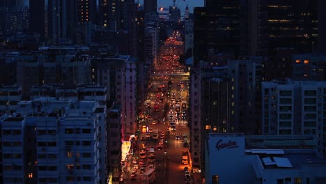 Beautiful-day-to-night-time-lapse-of-busy-street-surrounded-by-skyscrapers-with-cars-and-lights-moving-fast-with-motion-blur-while-city-illuminates-in-Hong-Kong