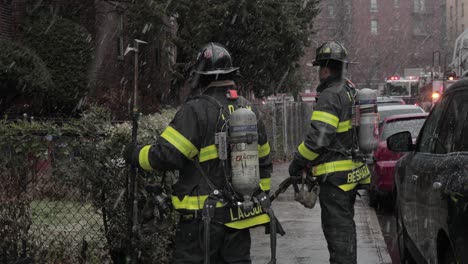 Firefighters-standing-under-heavy-snowfall-in-Brooklyn-street-attending-to-an-emergency---Medium-shot