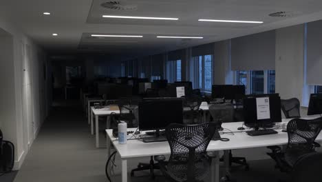 Halb-Beleuchtete-Reihen-Leerer-Schreibtische-Im-Bürogebäude-Während-Der-Sperrung