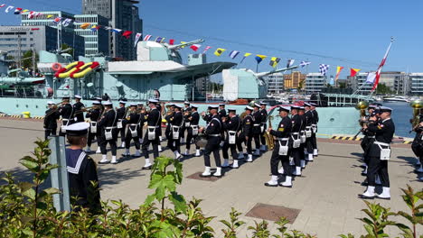 The-parade-of-the-military-naval-orchestra-in-Gdynia,-march-on-the-boulevard-by-the-ship-ORP-Blyskawica