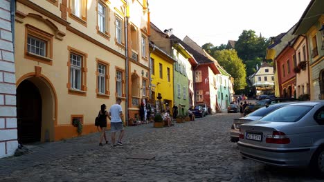 People-Sitting-And-Walking-On-A-Cobblestone-Street-In-The-Historical-Center-Of-Sighisoara-In-Romania,-static-shot