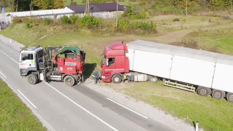 Driver-Attaching-Towing-Vehicle's-Rope-to-Semi-Truck-on-the-Roadside