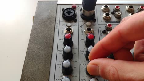 Microphone-cable-being-connected-with-XLR-connector-to-a-mixing-desk-channel-input-and-the-equalizer-knobs-are-turned