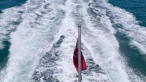 Australian-Red-Ensign-Flag-Waving-Against-Waves-From-Boat-Sailing-In-Open-Waters