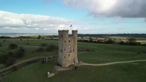 Dynamic-fast-aerial-push-over-to-top-down-at-Broadway-tower,-an-English-landmark-stood-atop-Beacon-Hill-in-the-Cotswolds,-UK