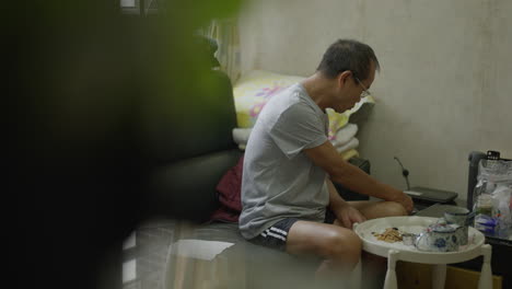 Old-Chinese-man-breakfast-in-the-living-room-of-a-cramped-apartment