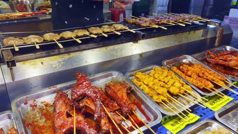 Close-up-shot-over-traditional-Asian-street-food-barbecue-food-on-display-on-wooden-stick-at-a-roadside-market-in-Kuala-Lumpur,-Malaysia