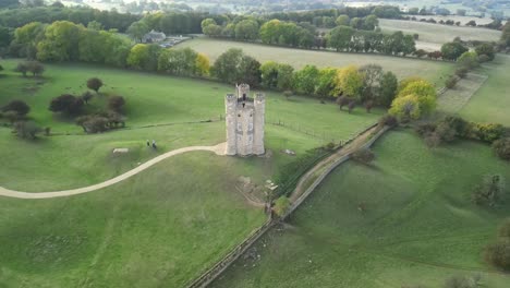 Dramatic-wide-aerial-push-into-top-down-shot-of-Broadway-tower,-an-English-landmark-stood-atop-Beacon-Hill-in-the-Cotswolds,-UK