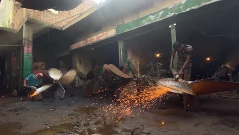 Hand-held-shot-of-men-grinding-down-ship-propellers-in-a-workshop-in-Dhaka