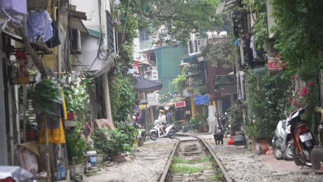 Vida-Cotidiana-En-La-Calle-Del-Tren-Con-Lugareños,-Motos,-Perros-Y-Niños-En-El-Famoso-Casco-Antiguo-De-Hanoi,-Vietnam