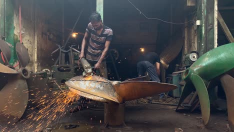 Hand-held-shot-of-a-ship-worker-using-an-angle-grinder-on-a-large-ship-propeller