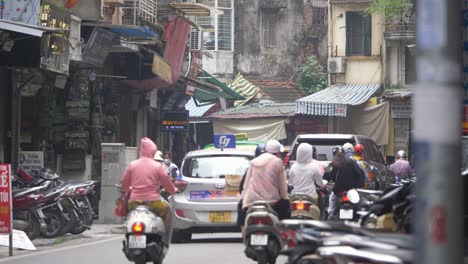 Busy-and-loud-street-with-motorcycles-and-traffic-in-famous-Old-Quarter-in-Hanoi,-Vietnam