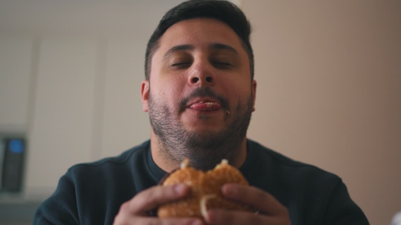 Vídeo Premium Aliviado Joven Hambriento Comiendo Una Hamburguesa