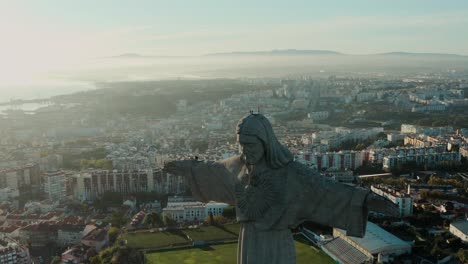 Big-Christ-monument-in-city-of-Lisbon-at-sunset,-drone-footage-of-Jesus-statue