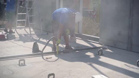 Construction-worker-vacuuming-dust-from-hole-drilled-into-concrete-pad