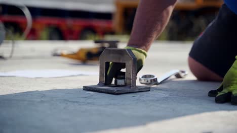 Hand-tightening-nut-on-screw-of-steel-anchor-bolted-into-concrete-pad