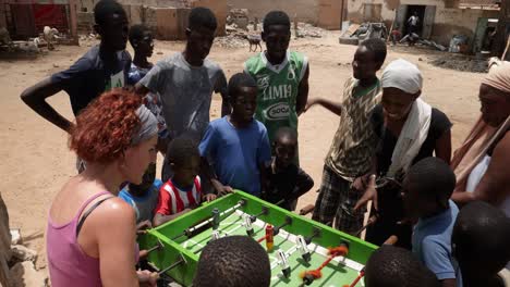A-white-and-a-black-women-compete-playing-table-soccer-in-the-street-of-Nouakchott,-Mauritania