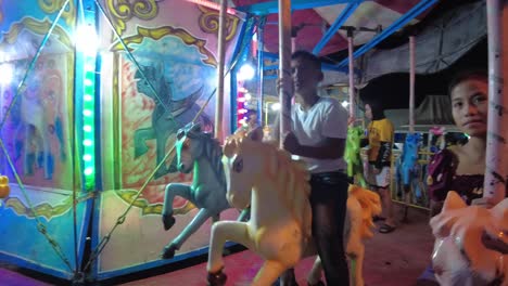 A-dynamic-handheld-shot-of-kids-enjoying-the-ride-on-the-horses-in-a-merry-go-round