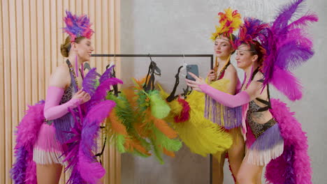 Dos-Bailarinas-De-Cabaret-Eligiendo-Los-Atuendos-Para-El-Espectáculo-Y-Su-Colega-Se-Toma-Una-Foto-Selfie-Con-Ellos