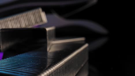 An-extreme-close-up-of-blocks-of-staples-with-a-stapler-in-the-background-illuminated-by-a-purple-and-blue-light-with-a-black-background