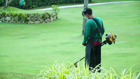 Asiatischer-Arbeiter-Schneidet-Gras-Mit-Grasschneider-Im-Garten-Eines-Luxushotels-Auf-Den-Philippinen