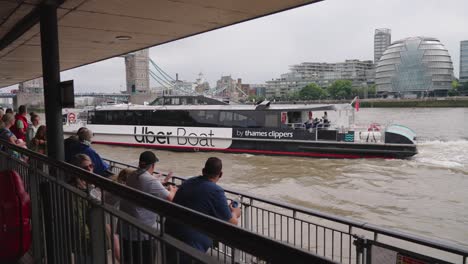 Waiting-Passengers-On-The-Dock-With-Uber-Boat-Arriving-On-The-Thames-River-In-London,-UK