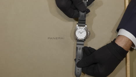Salesman-showing-luxury-Panerai-branding-nautical-wristwatch-front-in-retail-store-display