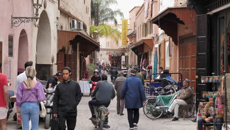 Street-activity-in-alley-of-Marrakesh-medina---tourists-wander-around,-Morocco