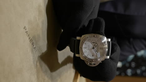 VERTICAL-Salesperson-hands-showing-expensive-Panerai-quality-wristwatch-workmanship-close-up-in-retail-boutique