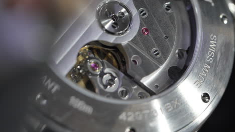 Moving-mechanical-parts-on-back-of-Cartier-luxury-wristwatch-clockwork-mechanism,-Slow-motion