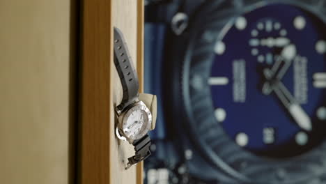 Vertical-video-of-watch-displayed-on-surface-with-giant-watch-poster-behind