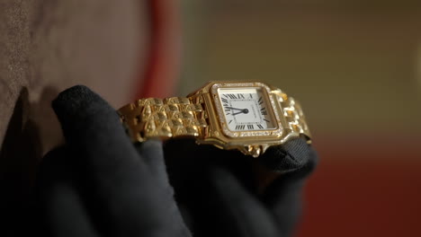 Thief-with-black-gloves-holding-expensive-golden-watch,-close-up-view