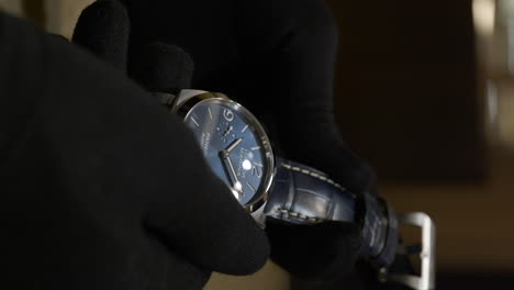 Person-touch-luxury-watch-with-gloves,-close-up-vertical-view