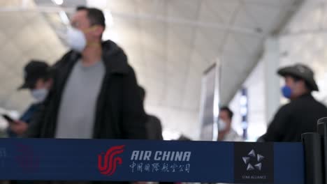 Chinese-flag-carrier-Air-China-airline-logo-is-seen-on-a-queue-belt-in-the-foreground-as-flight-passengers-line-up-at-a-check-in-desk-counter-at-the-Chek-Lap-Kok-International-Airport-in-Hong-Kong