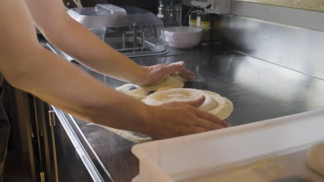 Zoom-in-shot-of-a-chef-kneading-pizza-dough-on-a-restaurant-kitchen-counter