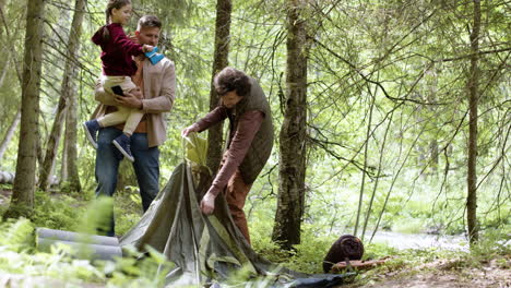Young-family-setting-up-tent-near-the-river