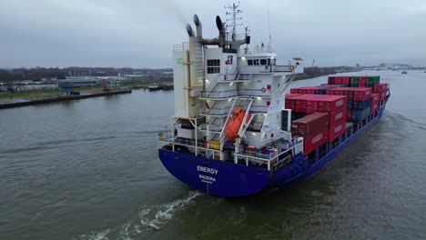 Aerial-Shot-Around-Stern-Of-Energy-Cargo-Ship-Carrying-Viasea-Intermodal-Containers-Passing-Along-Oude-Maas