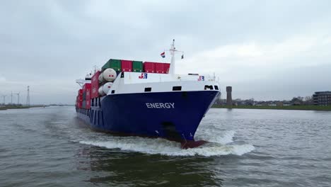 Aerial-Flying-Close-Around-Forward-Bow-Of-Energy-Cargo-Ship-Carrying-Viasea-Intermodal-Containers-Passing-Along-Oude-Maas