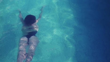 Eine-Schlanke-Frau-Schwimmt-Unter-Wasser-Weg-Von-Der-Kamera