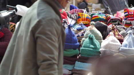 Slow-motion-shot-of-a-colorful-hat-stand-as-people-walk-by-in-street-bazaar