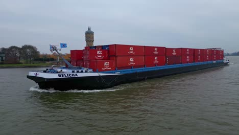 Aerial-Tracking-Shot-Alongside-Belicha-Inland-Freighter-Transporting-Intermodal-Containers-Sailing-Along-Oude-Maas-Through-Dordrecht