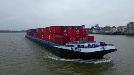 Aerial-Circle-Dolly-Around-Forward-Bow-Of-Belicha-Inland-Freighter-Transporting-Intermodal-Containers-Along-Oude-Maas