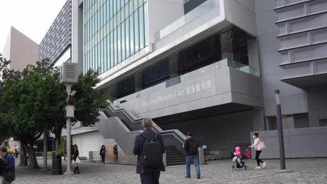 Hong-kong-museum-of-art,-modern-building-with-stairs-and-people-walking-on-the-street