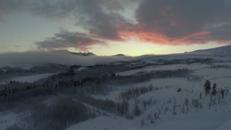 Scenic-arctic-wilderness-covered-in-snow-and-mist,-sunset-drone-flight