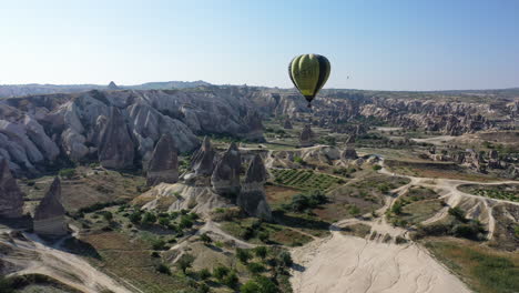 Epic-cinematic-revealing-drone-shot-beside-a-hot-air-balloon-and-revealing-the-city-of-Cappadocia,-Turkey